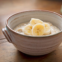 photo of a bowl of oatmeal with sliced bananas and frozen yogurt