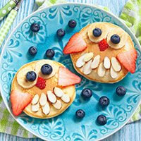 photo of Silly Pancakes - owls made up of different berries and nuts, decorating round pancakes.
